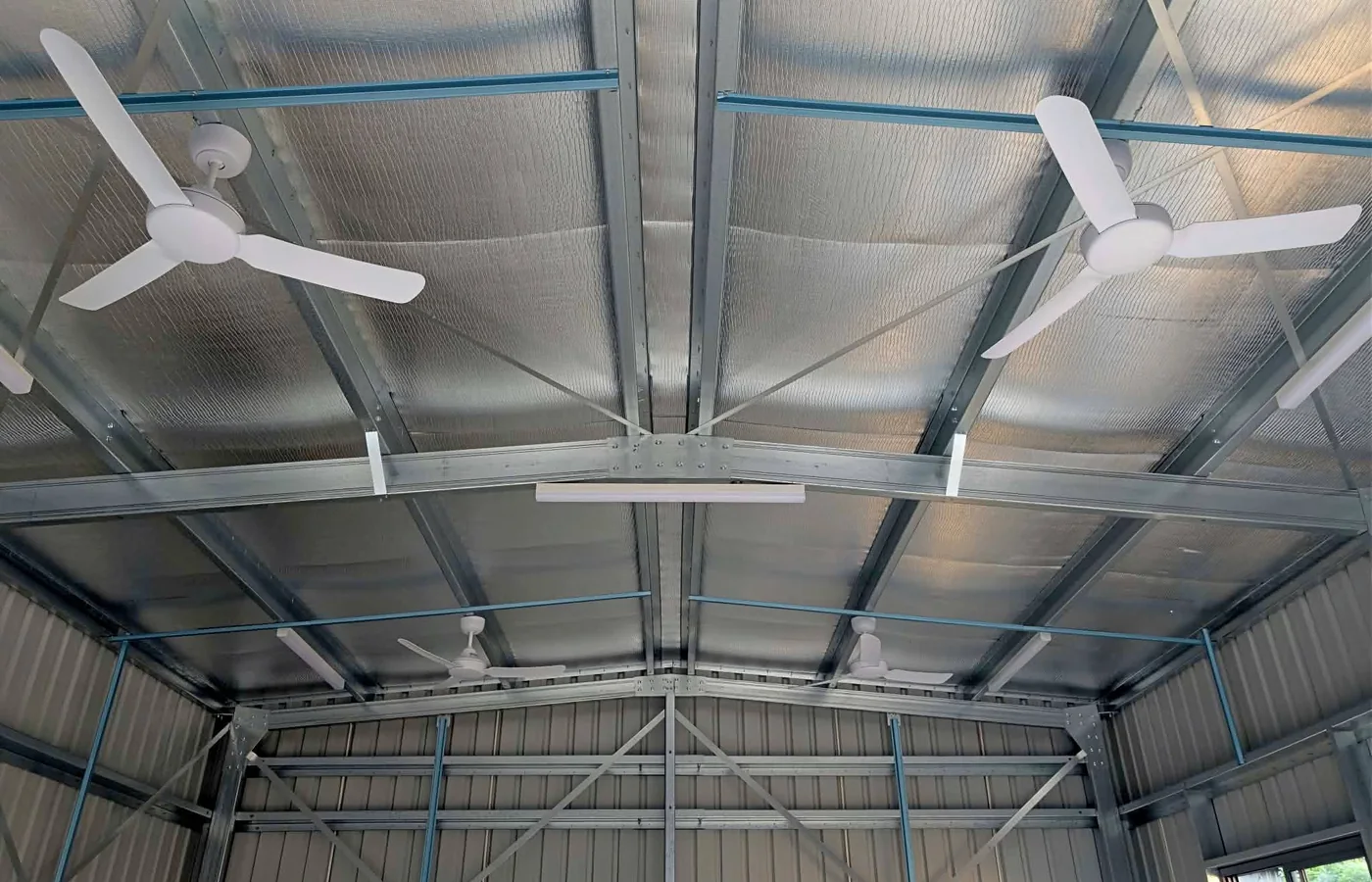 Multiple ceiling fans installed in a large shed/workshop.